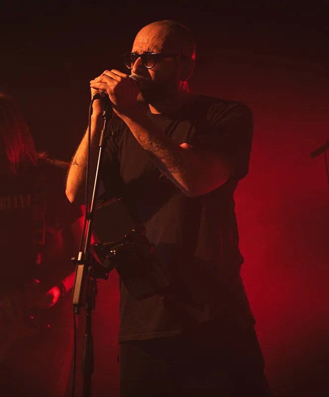 D-DOC al microfono sotto le luci rosse del palco, con la band alle spalle
