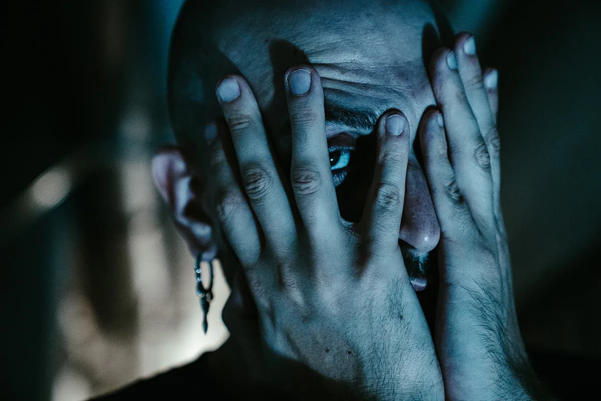 Primo piano di D-DOC con le mani sul viso e un occhio che spunta tra le dita